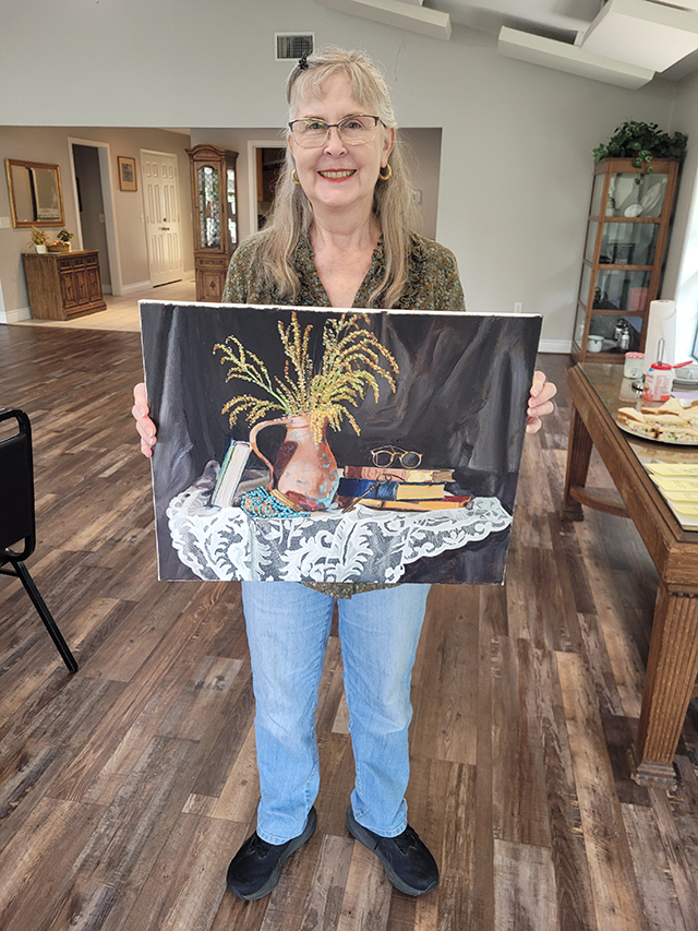 Photo of Toni holding her painting.